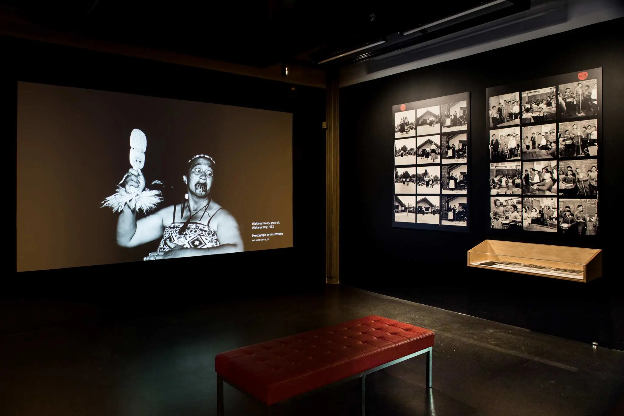 Images on a wall, including a woman with a club and enlarged photo contact sheets.