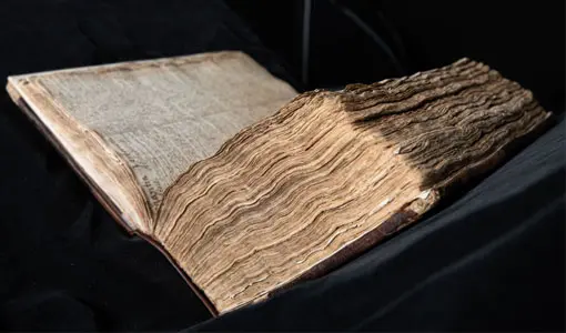 An old book with yellowing pages is open at a 45 degree angle ready to be digitised. 
