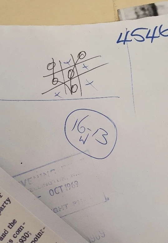 A cat's game of moughts and crosses scribbled in black ink on the back of a paper, along with other random numbers.