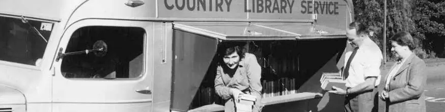 Men and women  with piles of borrowed books standing outside a mobile library.
