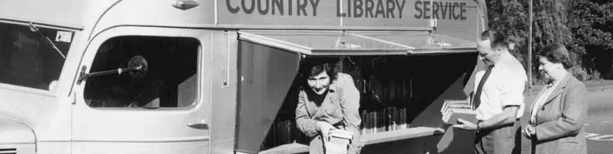 Men and women with piles of borrowed books standing outside a mobile library.