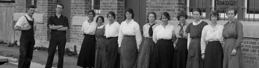 A group of women and two men stand outside a brick factory. 