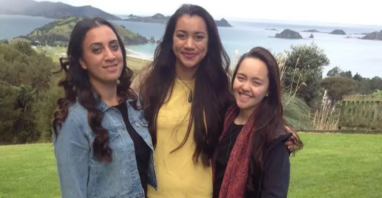 Three kura kaupapa students with Matauri Bay in the background.