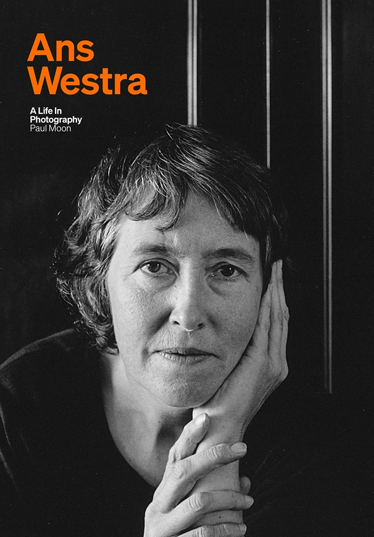 Book cover with a black and white photo of a woman resting her head in her hands and the text 'Ans Westra: A life in photography' in orange. 