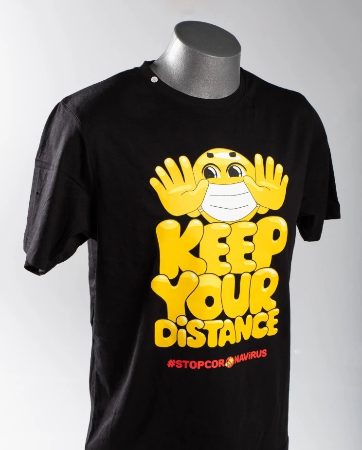 A black shirt with a smiley face wearing a mask reads, 'Keep your distance. #stopcoronavirus'.