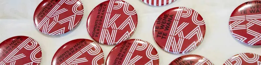 Red and white badge with the words Pūkana on it.