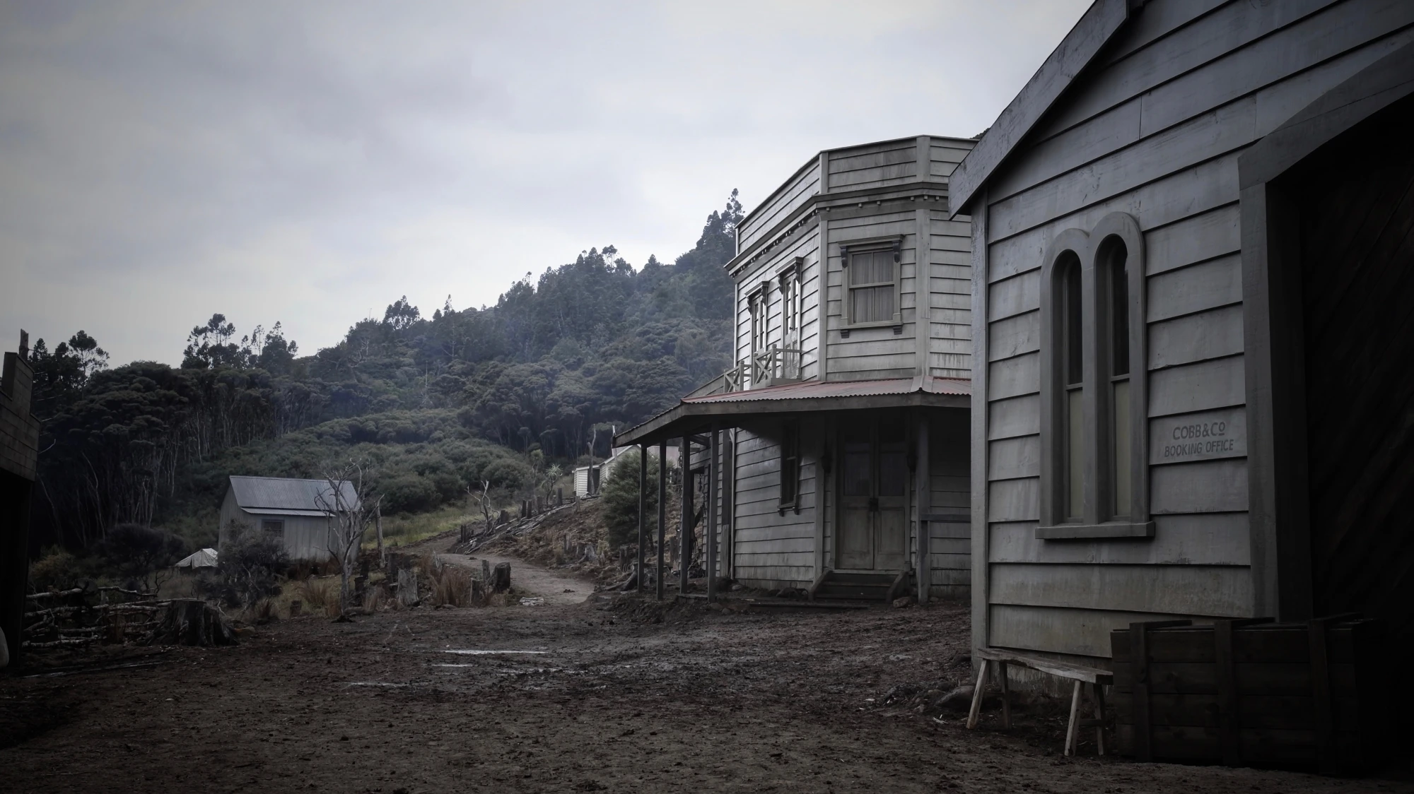 Completed set with wooden buildings along a rutted, muddy street.