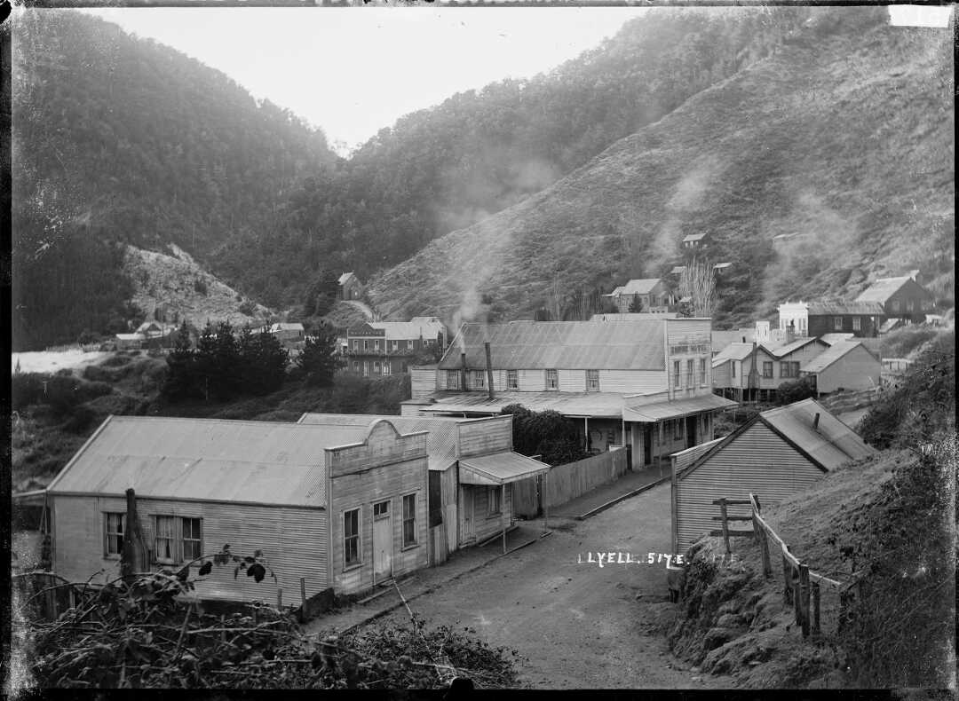 A view of a small town with dirt main street and smoke coming from the various chimneys.