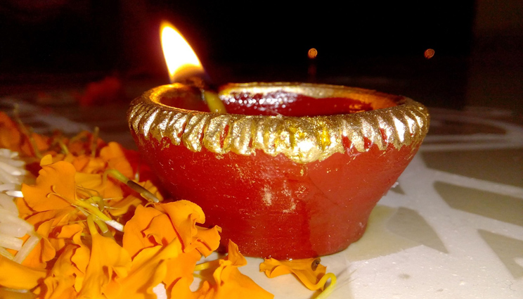 Burning Diwali candle and yellow flower petals
