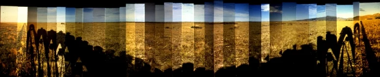 A photomontage of a flat, grassy landscape with distant hills and a man's shadow being cast at different lengths throughout the day.