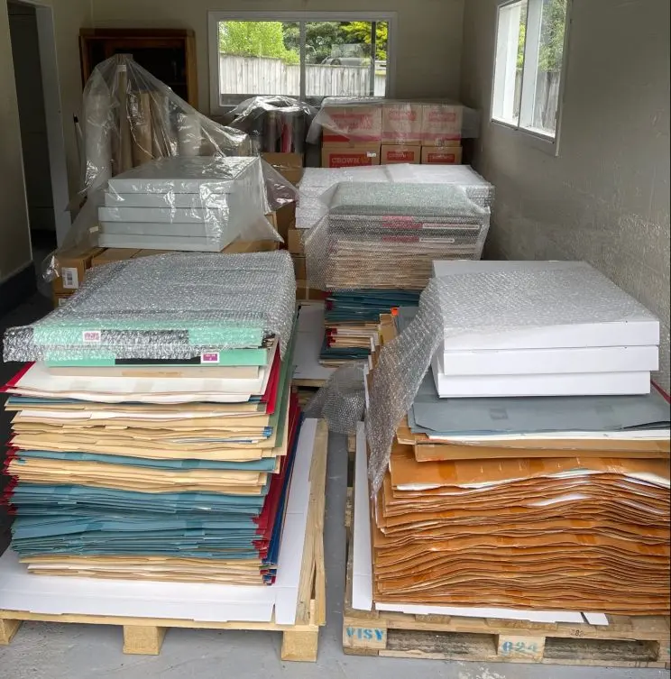 A room filled with various stacks of large maps, including two pallets stacked waist high with maps. 