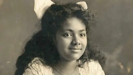 A black and white portrait of a young girl with a ribbon in her hair. 