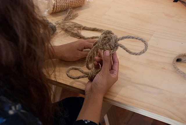 A woman holding a decorative knot.