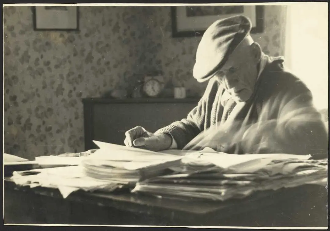 Photograph of James Cowan at his desk writing. 