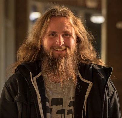 Man with long hair and beard smiling. 