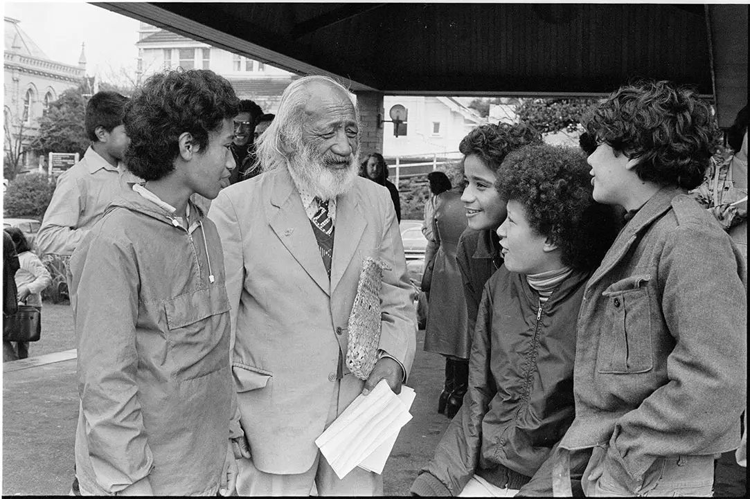 Black and white photo of Hēmi Pōtatau (Ngāti Kahungunu, Ngāti Rākaipaaka) holding a petition and meeting with students in 1978.