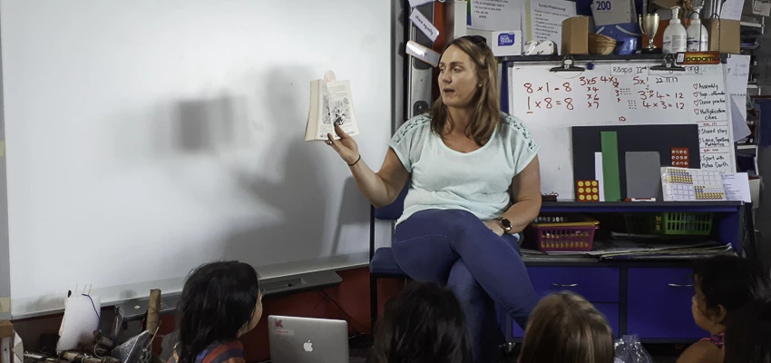 School teacher reading aloud to school students