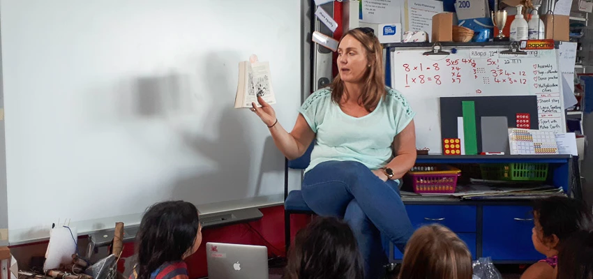 School teacher reading aloud to school students