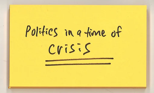 Post-it note with words "Politics in a time of crisis" written on it. 