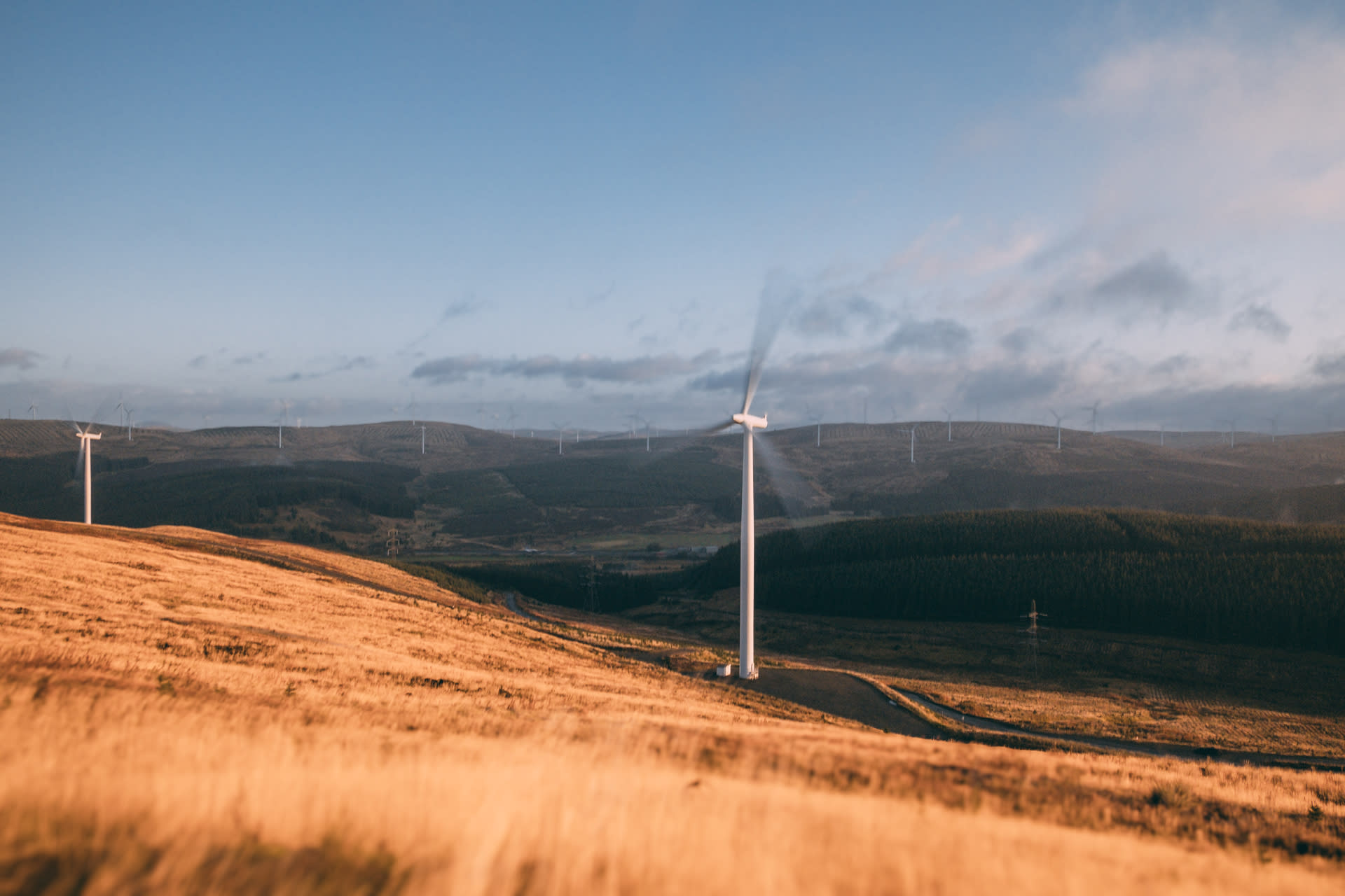 Rolling hills with clouds in the sky and a wind turbine