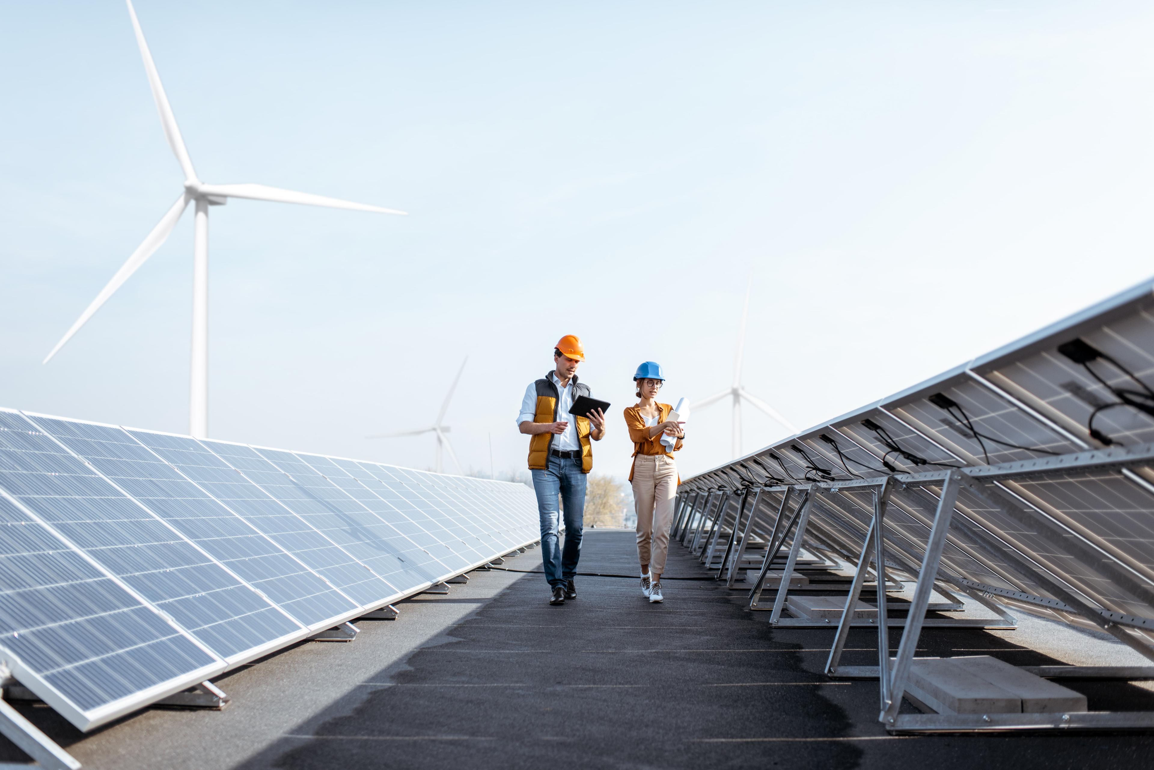 A man and woman walking along a wind turbine.