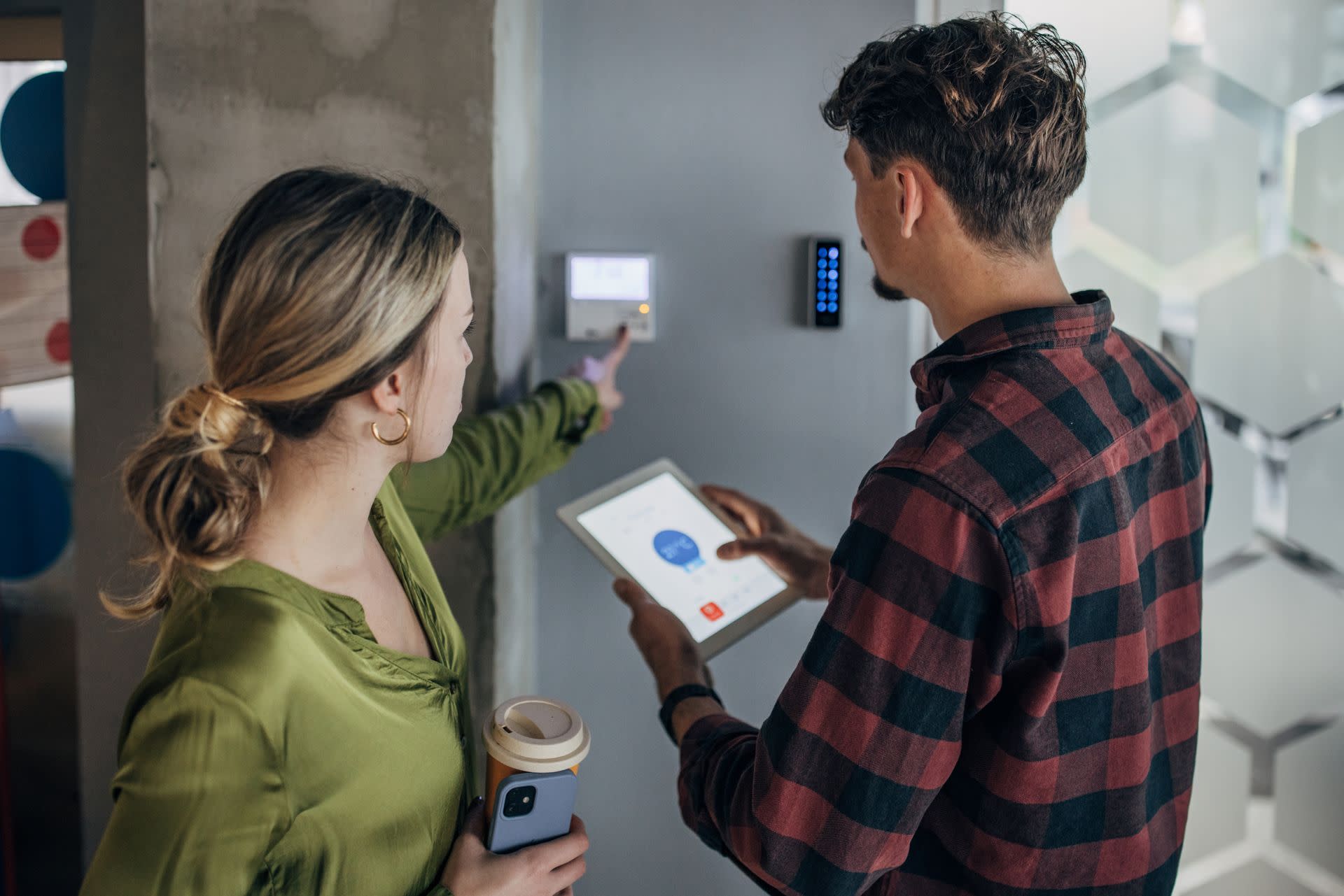 A man and a woman looking at a small screen on the wall displaying information