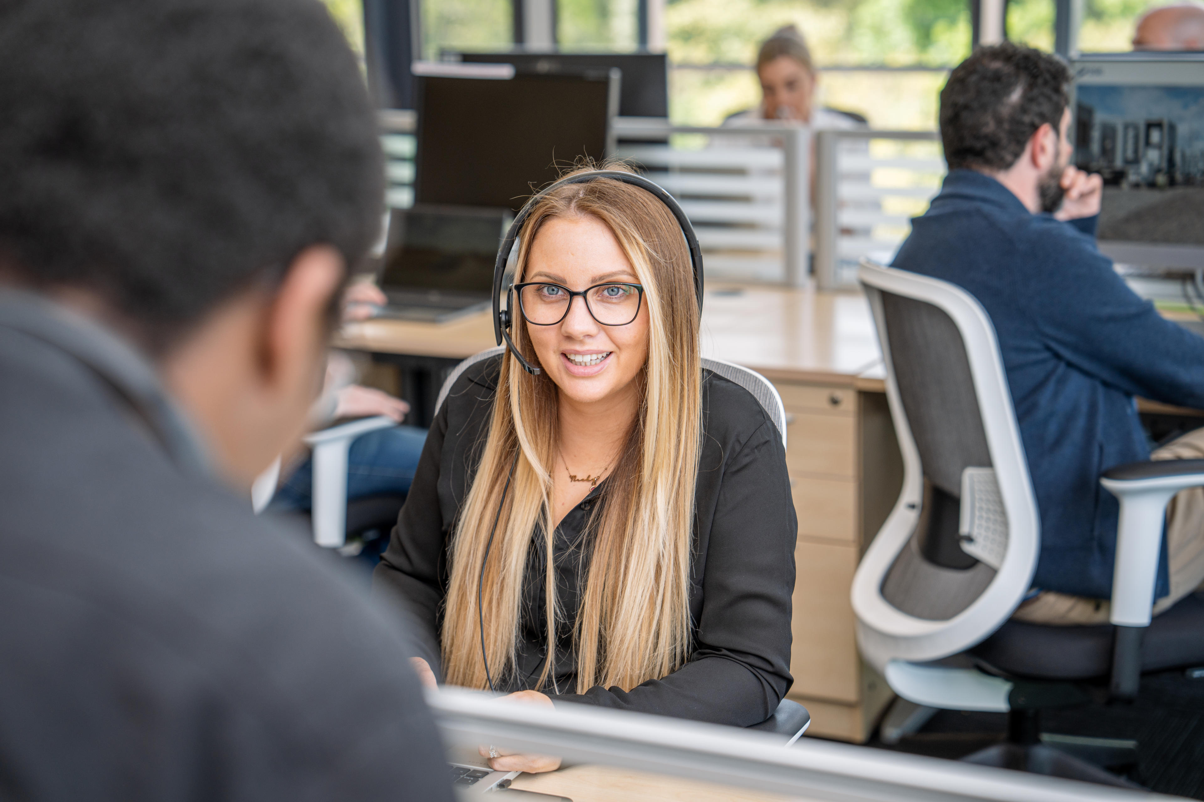 Customer service employee wearing a headset and smiling while on a call.