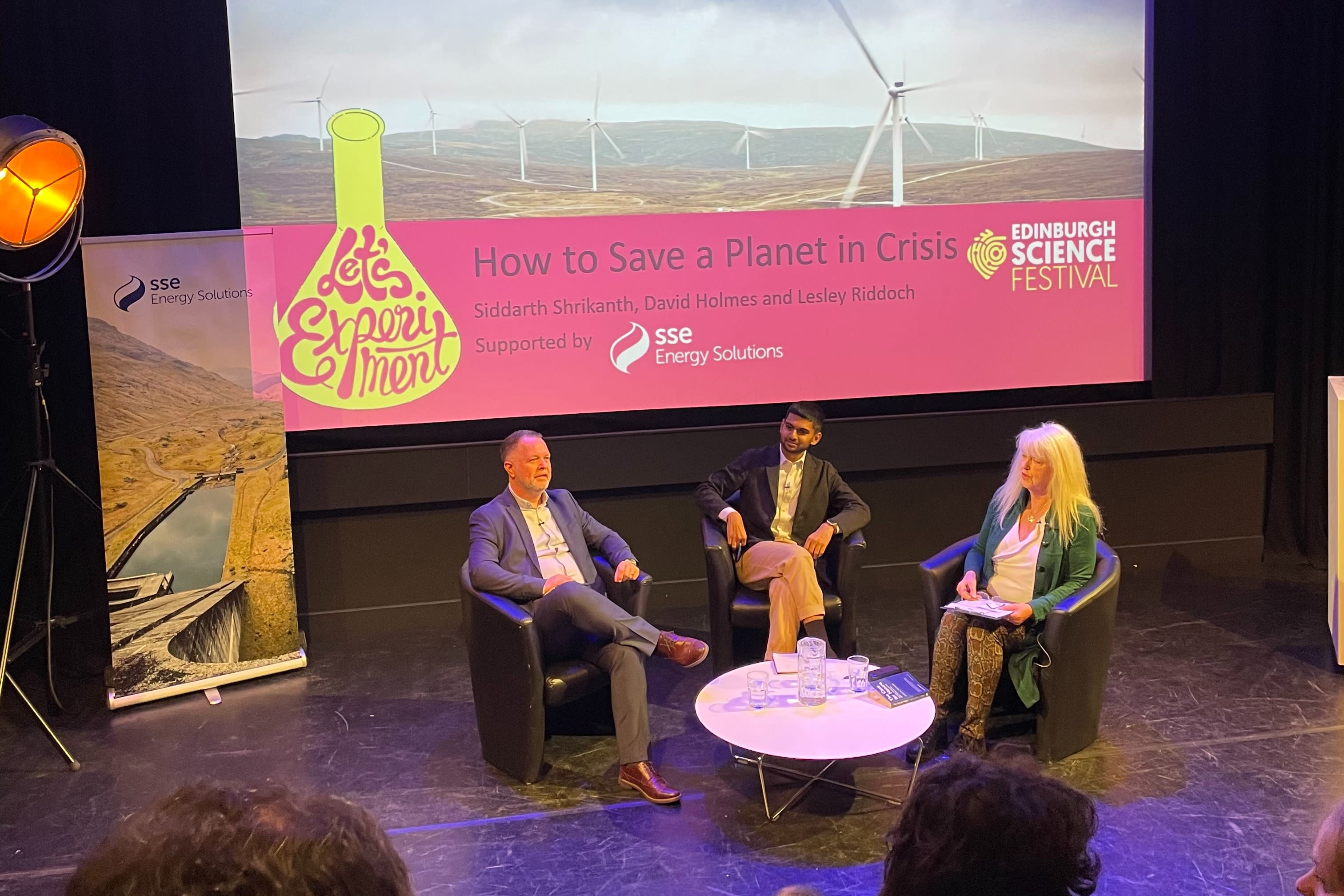 Image of David Holmes, Siddarth Shrikanth and Lesley Riddoch on stage in front of a screen at an Edinburgh Science Festival Event 