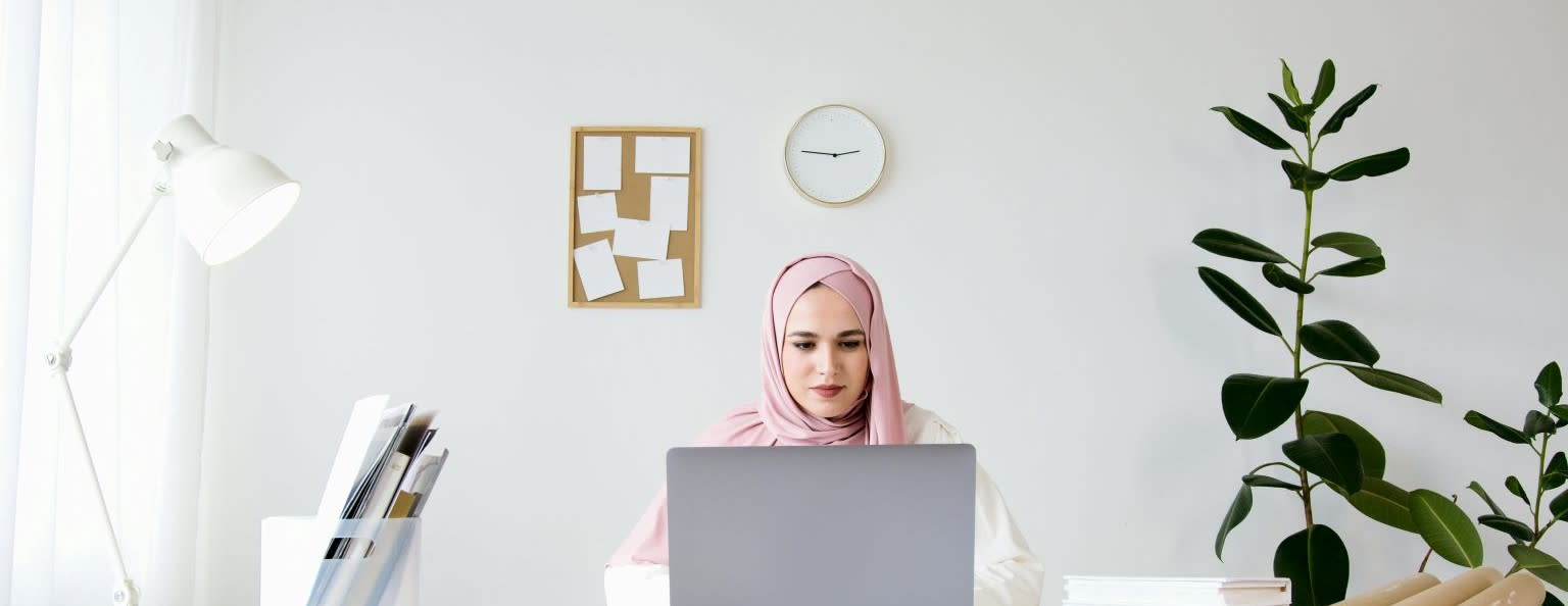 A lady sat at a desk, looking at her laptop.