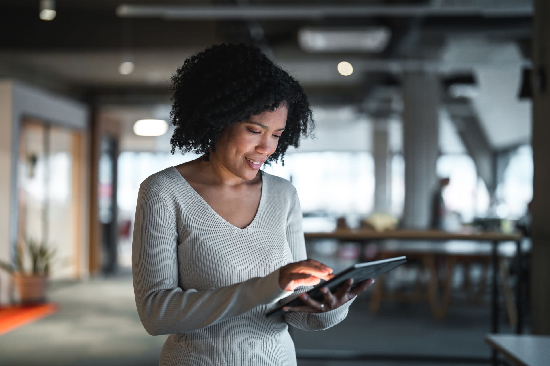 Lady in a corporate setting is touching a tablet screen with her fingers