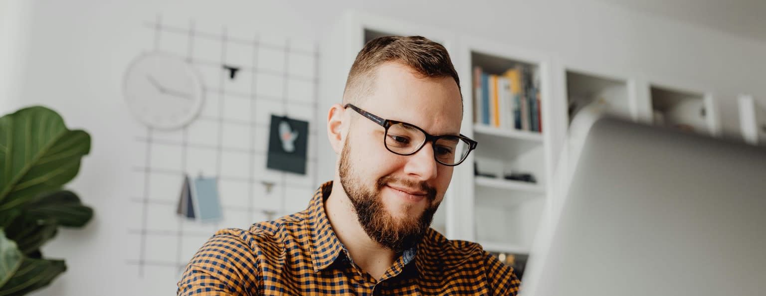 A man smiling as he looks down at his laptop in a corporate environment