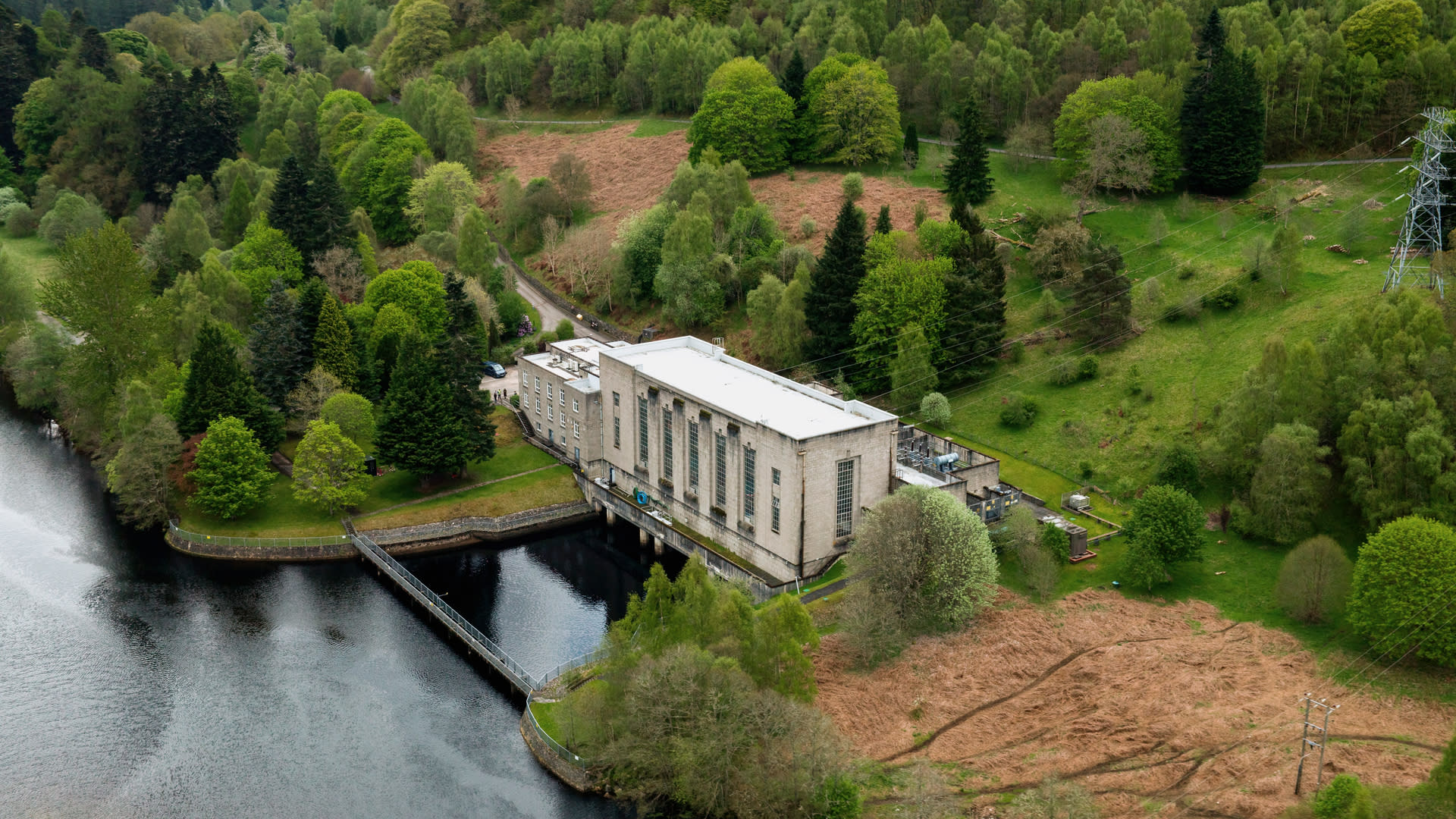 Drone image of river and a hydro energy facility, surrounded by greenery