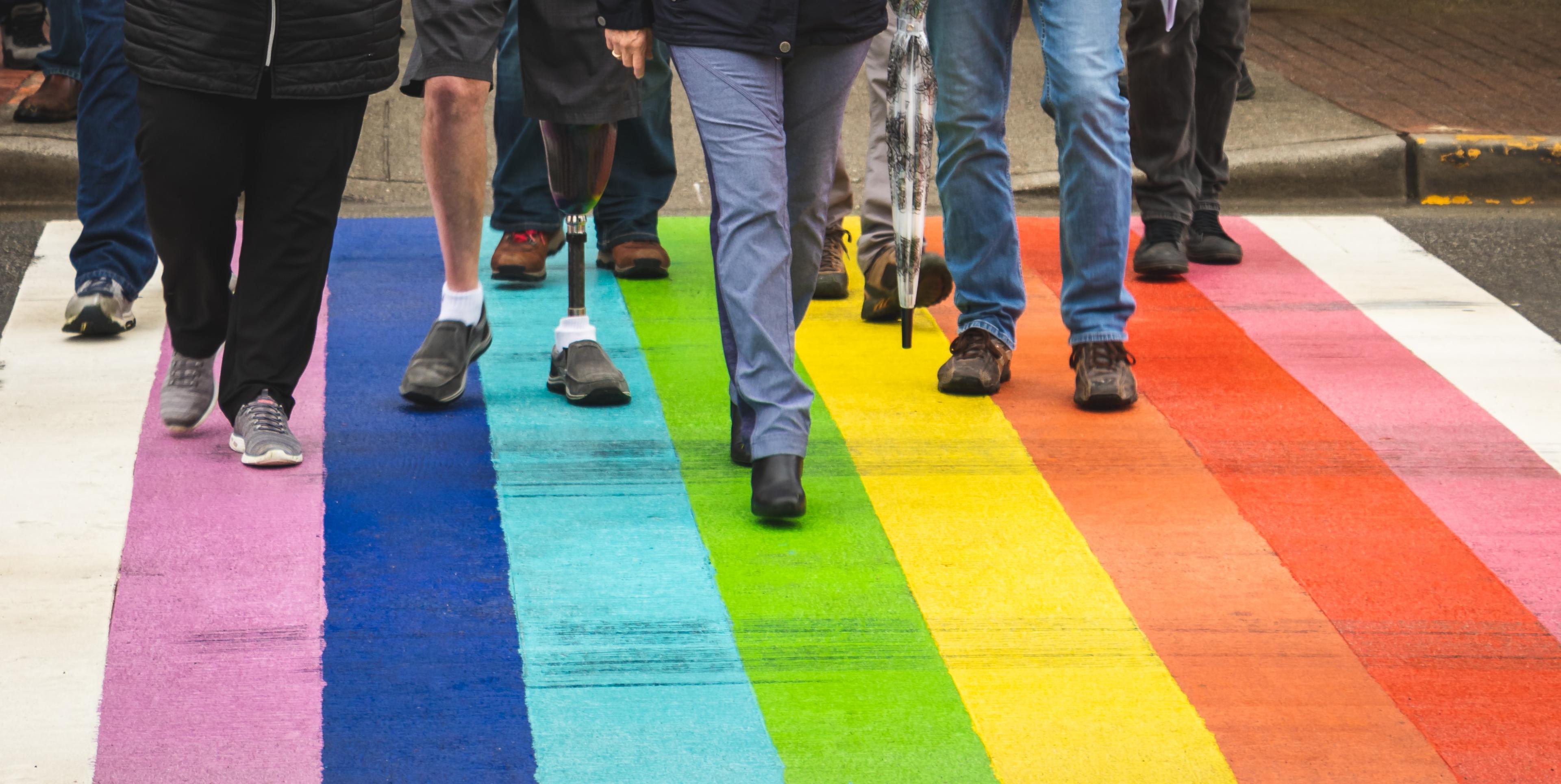 People walking across a rainbow pedestrian crossing