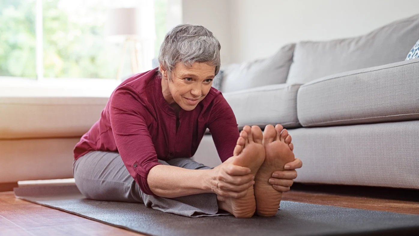 Adulta mayor haciendo ejercicios de estiramiento en una colchoneta de yoga