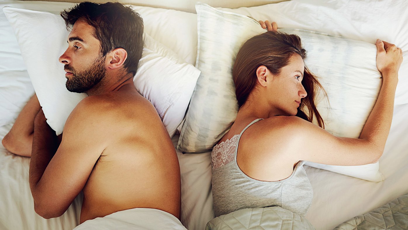 Man and woman facing away from each other in bed