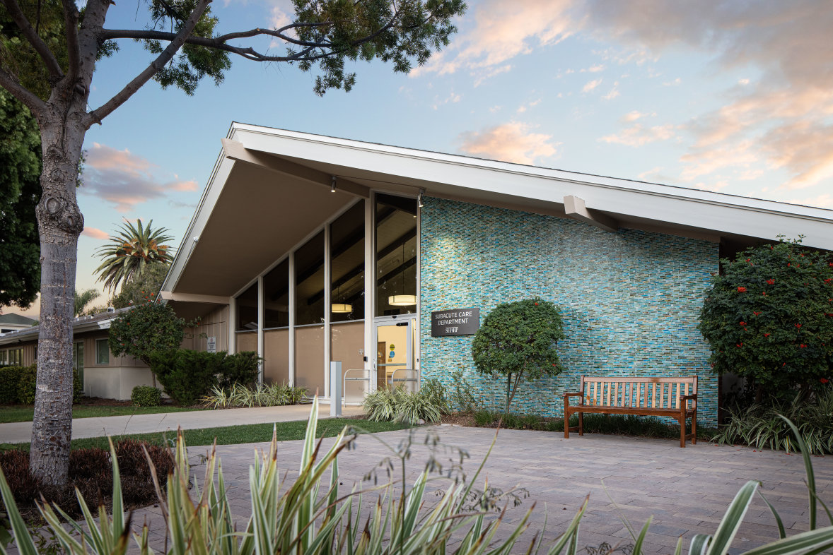Exterior of Sharp Coronado subacute care unit with trees and bench in front of entrance
