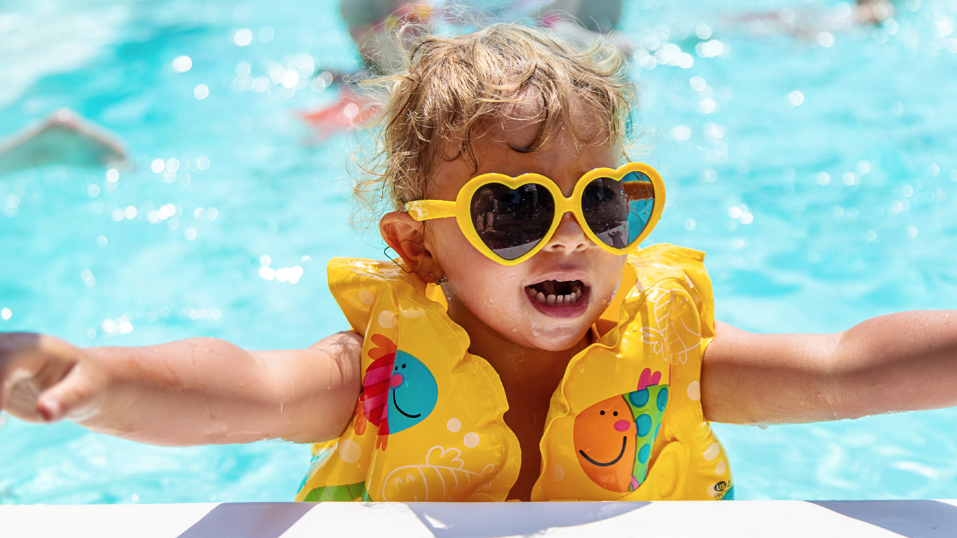 Child in pool wearing sunglasses and a safety vest