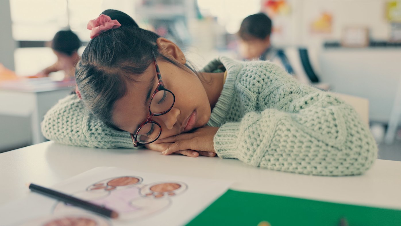 Child sleeping at her desk at school