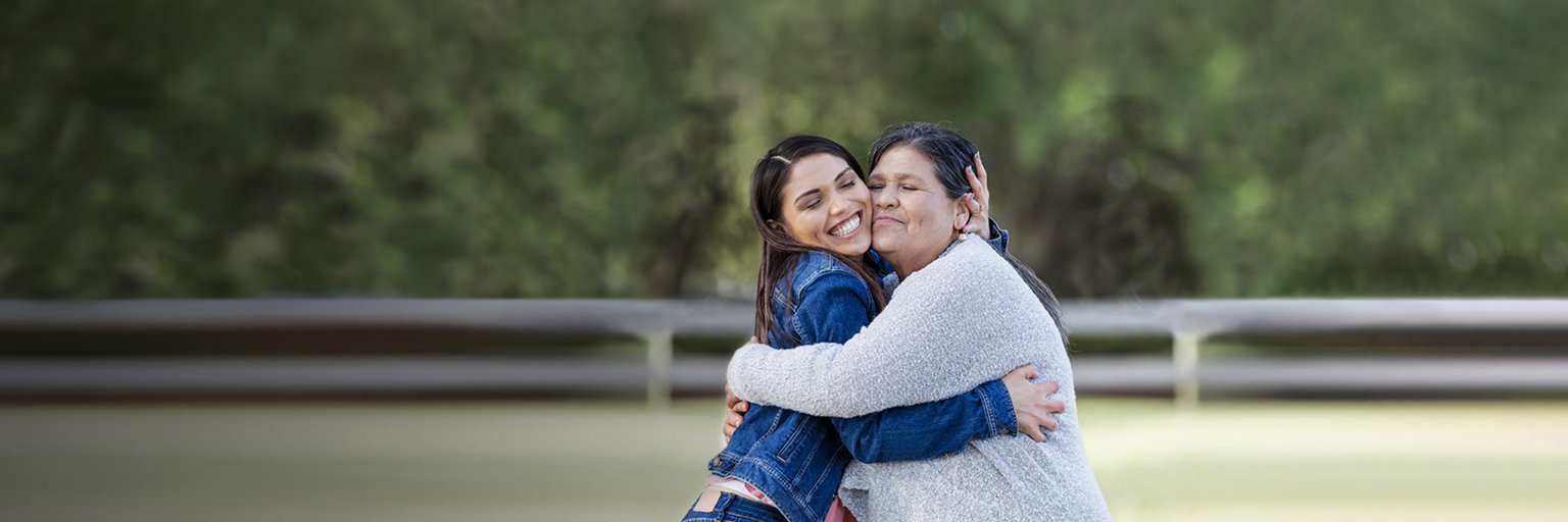 Young woman on left hugging older woman on right