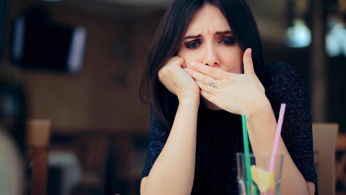 Woman feeling sick and covering her mouth