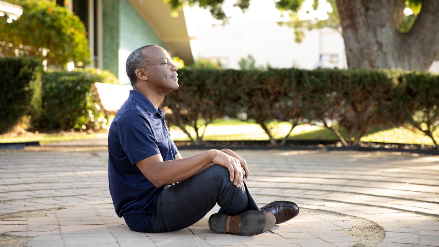 Man meditating, sitting in labyrinth on Sharp Coronado Hospital campus.