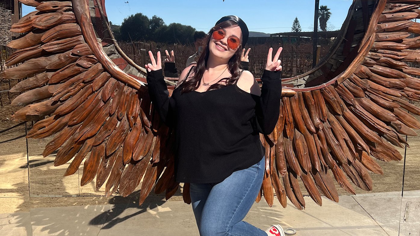 Alexis Fairchild of San Diego posing at a winery in front of a wooden sculpture of wings