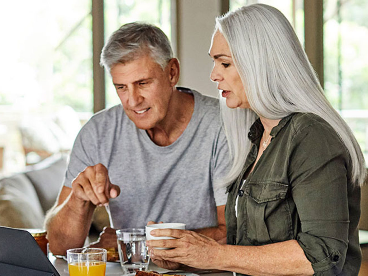 Senior couple having breakfast while looking at a tablet