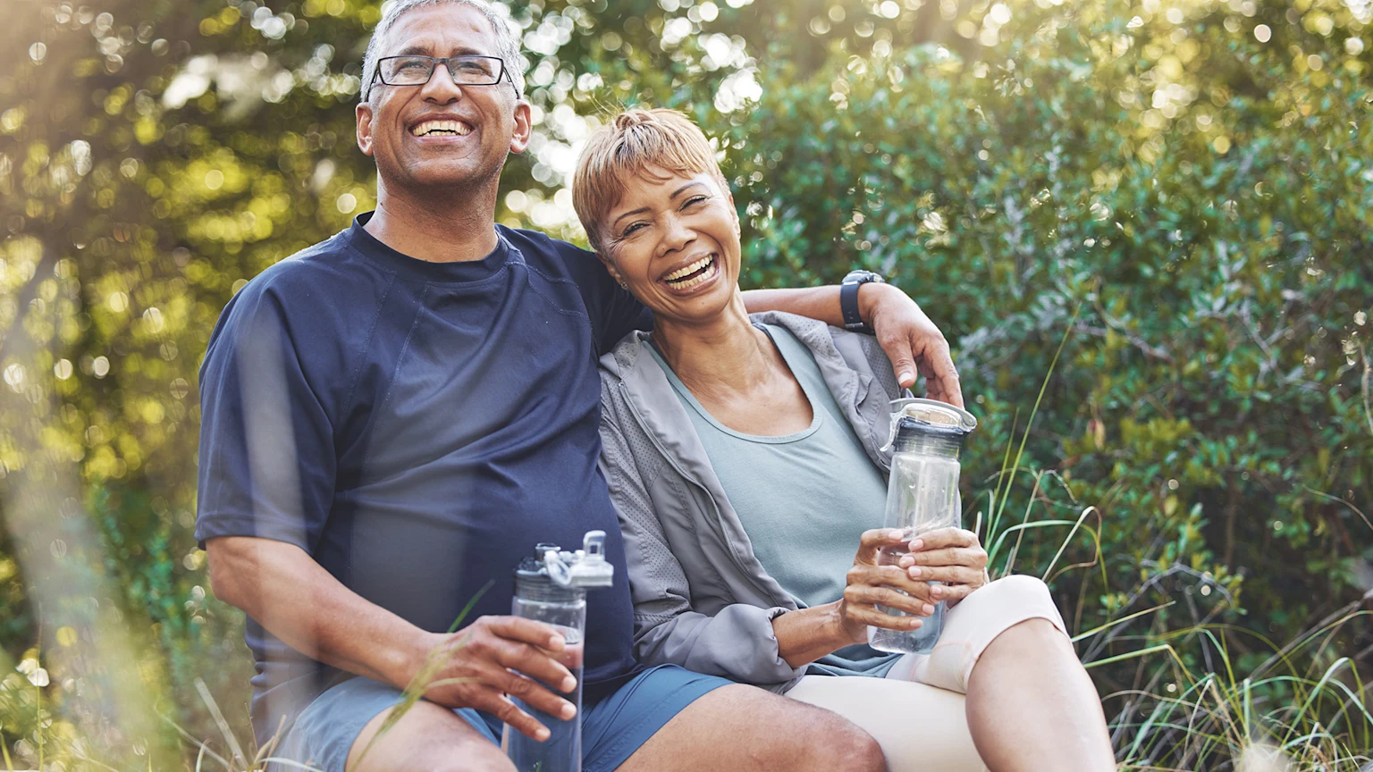Happy couple outdoors drinking water