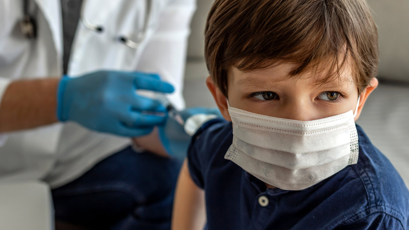 Child in mask getting a shot from a doctor