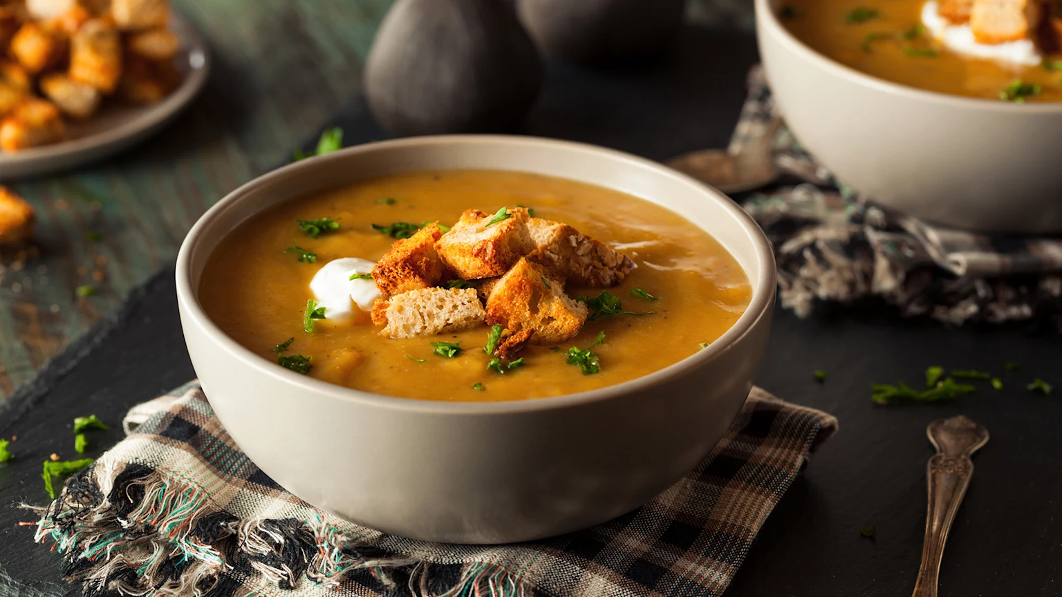 Carrot soup in a bowl with croutons and sour cream
