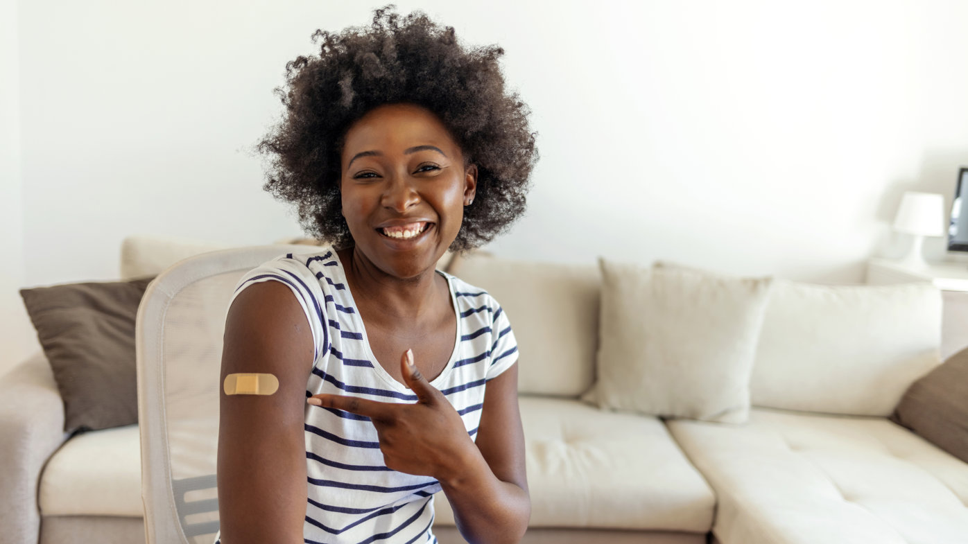 Woman pointing to her vaccine bandage