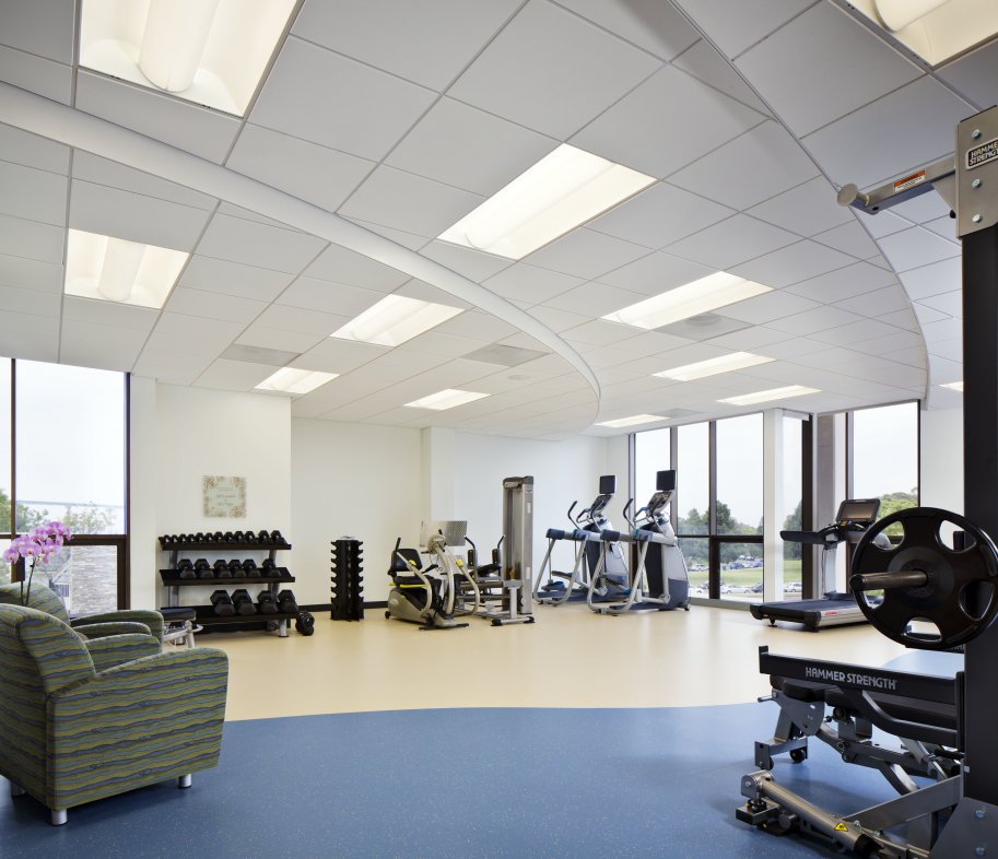 Fitness center with treadmills, exercise bike and weights in the background and a green chair and weight machine in the foreground