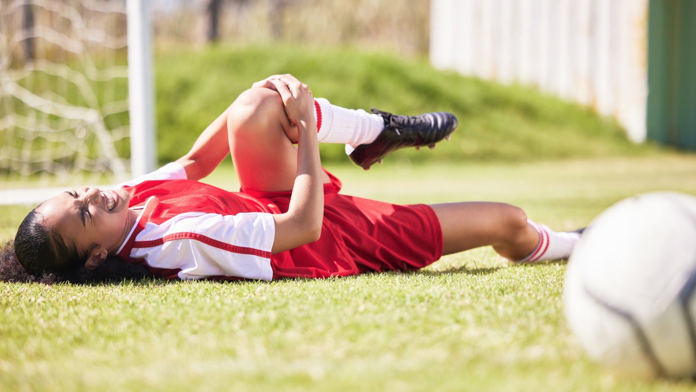 Soccer player on the ground holding her knee in pain