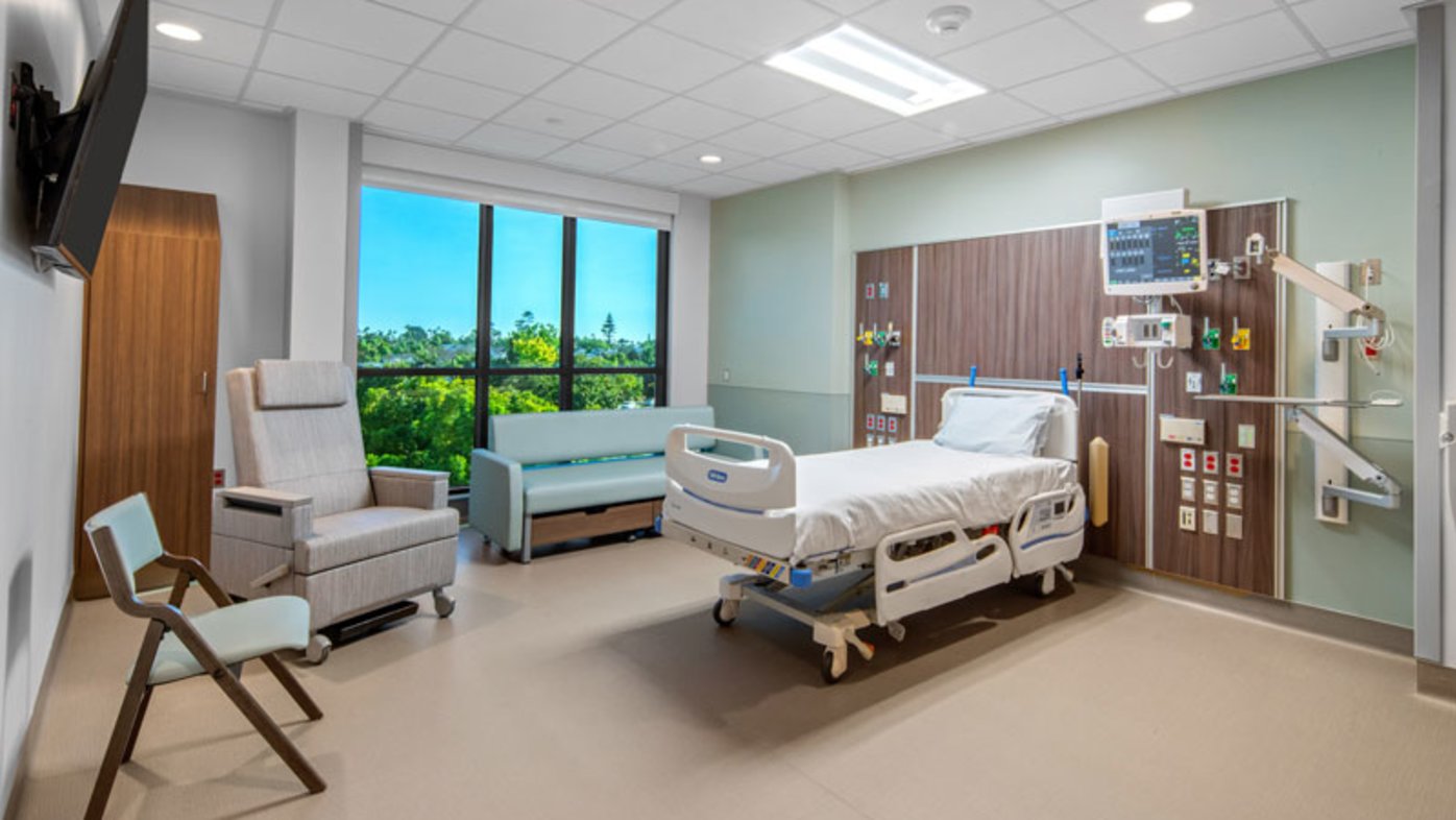 Patient room with bed, guest chair, couch and TV